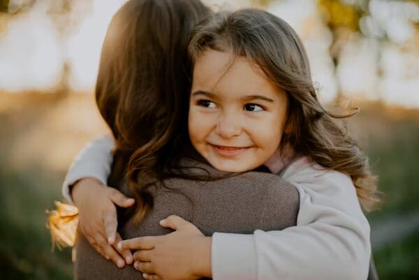 Young girl hugging adult.