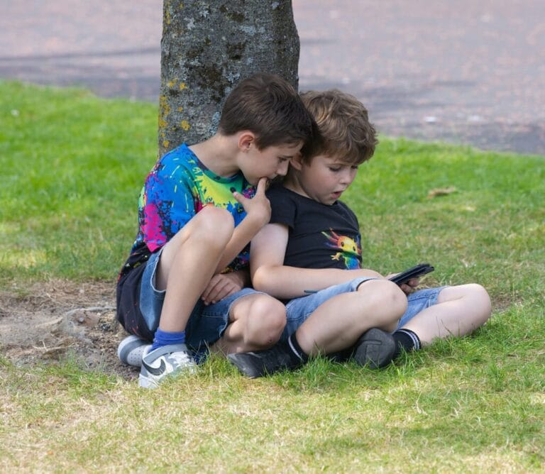 Two young boys looking at a phone.